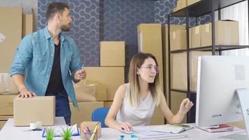 Order packages, taking orders in e-commerce, entrepreneurship. Entrepreneurial woman and man working in e-commerce office arrange cargo packages and check incoming orders from computer. video