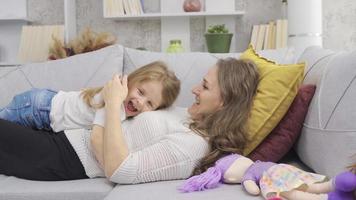 Mother and daughter lying down, hugging each other. Happy mother and daughter lying on sofa talking and laughing with each other. video