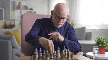 le vieux homme, qui vies seul et a non un, pièces échecs. le vieux homme est en jouant échecs par lui-même. video