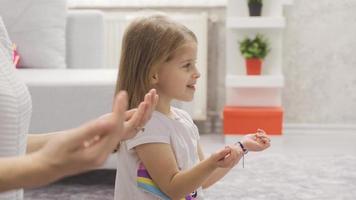 pequeño niña reza a dios. pequeño niña aprende a Adoración con su madre a hogar y reza a dios. video