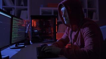 Male hacker using computer to commit a crime. Hacker sitting near computer monitors with green code screens. video