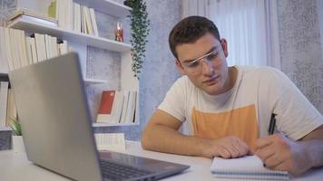 estudiante estudiando en computadora. él es haciendo investigación. Universidad estudiante estudiando a hogar. video
