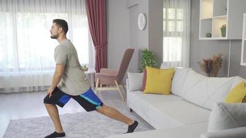 joven deportivo masculino hacer ejercicio en vivo habitación interior. hombre haciendo Deportes a hogar haciendo calentar ejercicios. video