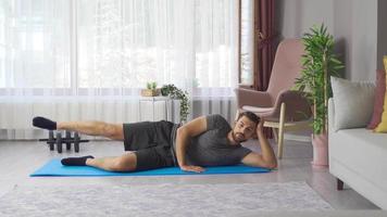 Young athletic man training at home stretching stretching legs. He does the crunches, works hard to isolate his body shape. video