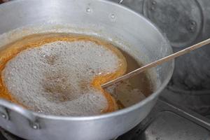 Making Thai dessert Golden Egg yolk threads or Foi Thong in a pot with boiling syrup. photo