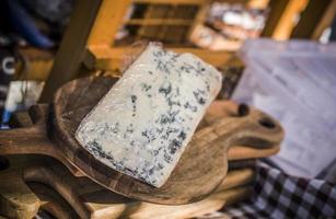 A piece of French cheese with blue mould on a wooden board being sold photo