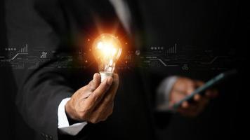 Hand of businessman holding illuminated light bulb with network connection line, idea, innovation and inspiration concept. concept creativity with bulbs that shine glitter. photo