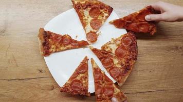 Top view human hands taking slices of pizza with cheese, tomatoes from food delivery. video