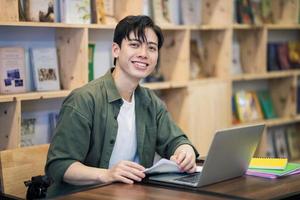 joven asiático hombre estudiando a biblioteca