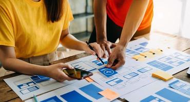 UX developer and ui designer brainstorming about mobile app interface wireframe design with customer breif and color code at modern office. photo