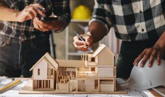 Close up shot of scale model house on table with architects. Two architects making architectural model in office together. to form a new building photo