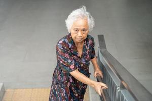 Asian senior woman patient use slope walkway handle security with help support assistant, healthy strong medical concept. photo