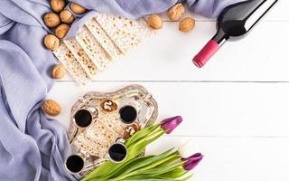 silver tray with glasses of red wine, nuts, matzah, flowers .top view. flat lay. a copy space. white background. the concept of the Jewish Passover. photo