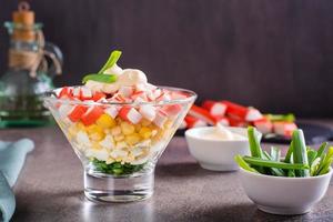 Crab salad of fish sticks, eggs, onions and corn in a bowl on the table photo