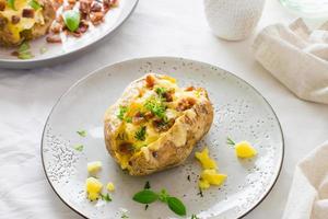 Appetizing twice-baked potatoes in their skins with cheese and bacon crumbs on plates on a wooden table. Flexitarian Diet. Close-up photo