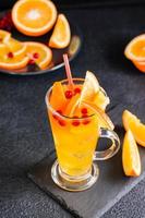 naranja arándano gaseoso cóctel en un vaso y frutas y bayas cerca en un pizarra en un oscuro antecedentes. hecho en casa cóctel sin alcohol vertical ver foto