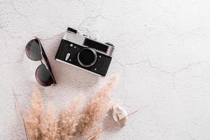 Flat lay concept travel. Vintage camera, sunglasses, stone and grass on a textured concrete background.