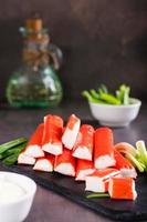 Minced fish crab sticks and green onions on a stone board ready to eat. Vertical view photo