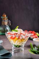 Crab salad of fish sticks, eggs, onions and corn in a bowl on the table. Vertical view photo