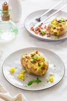 Twice-baked potatoes in their skins with cheese and bacon crumbs on plates on a wooden table. Flexitarian Diet. Vertical vew photo