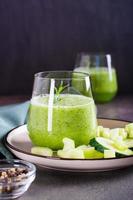 Fresh green cucumber and celery smoothie in glass for vegetarian diet vertical view photo