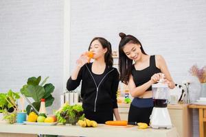 Asian active two women sibling in sportswear eat healthy food in kitchen. photo