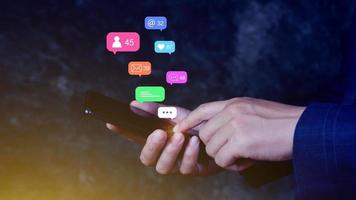 People using social media and digital online marketing concepts on mobile phones with icons such as notifications, messages, comments on the smartphone screen.