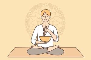 Meditating man sitting in lotus position on yoga mat using bowl to perform ancient ritual. Guy sits cross-legged near Buddhist symbol practices yoga and meditation to recuperate after work vector