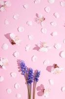 Pattern with delicate petals of plum and muscari flowers on a pink background. Spring vertical creative background photo
