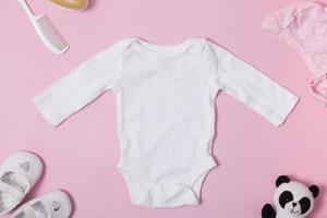 Children's clothing top view, white baby bodysuit mock-up on a pink background. Your text or logo place