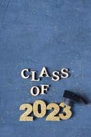 Graduated 2023 concept. Class of 2023 text with graduate cap on dark background with bokeh photo