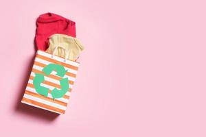 para niños ropa en compras bolso con un reciclaje símbolo. segundo mano, donación ropa reciclaje concepto foto