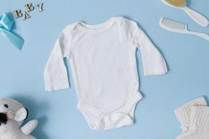 Top view of baby clothes, white baby bodysuit mockup on blue background. Place your text or logo photo