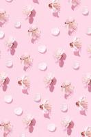 Pattern with delicate petals of cherry blossoms on a pink background. Spring vertical creative background photo