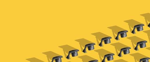 Pattern with black graduated cap on yellow background with copy space. Education background photo