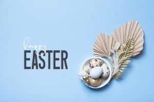 Happy Easter text with easter eggs, palm leaves and flowers composition. Easter flat lay photo