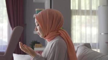 para rezar. muçulmano jovem menina Rezar para dela Deus. muçulmano mulher sentado às casa Rezar. video