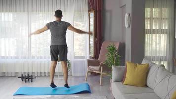 deporte, aptitud y sano estilo de vida concepto. joven hombre haciendo saltando Jack ejercicio a hogar. video