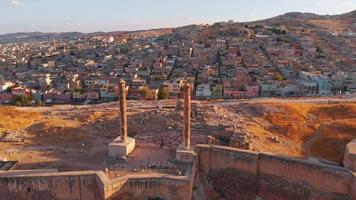 Aerial revealing zoom out view famous landmark dual columns on top Urfa castle with colorful old town tradition architecture colorful houses background video