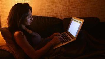 Woman using laptop checking write email, online blog, sitting on sofa. Internet social networks or working on computer, writing blog watching webinar, studying at home. Work at night late video