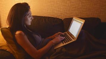 Vista superior de una mujer joven que usa una laptop, escribe sentada en el sofá en casa, una chica hermosa comprando o chateando en línea en las redes sociales, trabajando, comprando, freelancer trabajando en una computadora video