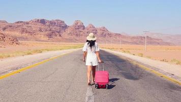 turista mulher andando arrastando mala de bagagem rosa vai viajar pelo mundo das férias de verão. estilos de vida e conceito de viagem. viajar na Jordânia video