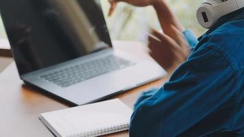 junger erwachsener glücklich lächelnder hispanischer asiatischer student mit kopfhörern, der über online-chat-meetings mit laptop auf dem universitätscampus oder im virtuellen büro spricht. College-Studentin, die aus der Ferne lernt. video