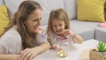 The girl with the piggy bank. The boy puts money into the piggy bank. Caring parent teaches kid to save money, think about future, manage personal finance, savings concept. video