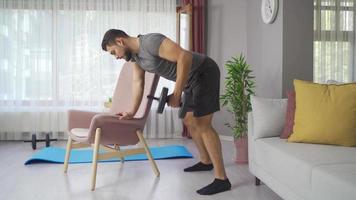 fare braccio formazione con manubri a casa. giovane uomo sollevamento pesi con manubri lavori per braccio muscolo. video