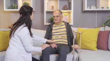 Positive female doctor is dealing with sick old man with friendly expression. Female doctor taking care of elderly man receiving home care service with a smile. video