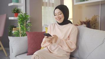 Muslim young woman texting on the phone. Young muslim woman texting on phone at home. video