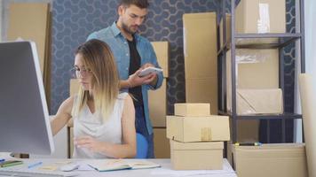 Entrepreneur woman packing e-commerce product order and sticking warning note. Woman checking product orders in e-commerce office and writing warning and informative tips. video