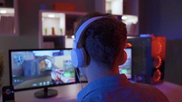 professioneel gamer spelen eerste persoon schutter online video spel Aan krachtig pc. jong jongen spelen een spel zittend in voorkant van een computer, vervelend koptelefoon.