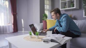 Happy male student looking at laptop and books. The male student who enjoys studying is happy. video